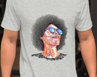 May include: A grey t-shirt featuring a graphic of a person with an afro wearing sunglasses. The person's face is made up of intricate patterns.
