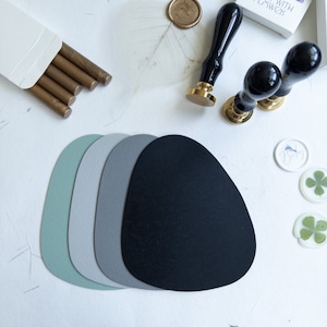 May include: A set of four round, textured coasters in shades of green, grey, and black. The coasters are arranged in a stack, with the black coaster on top. The coasters are made of a soft, absorbent material and are perfect for protecting your furniture from spills and scratches.