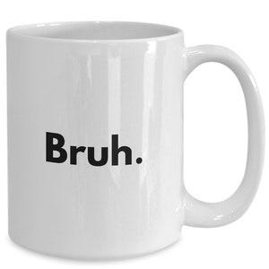May include: White ceramic coffee mug with a black inscription that reads "Bruh."