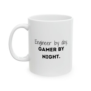 May include: White ceramic coffee mug with black text that reads "Engineer by day, GAMER BY NIGHT."
