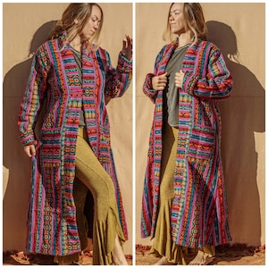 Peut inclure: Une longue robe à motifs colorés avec un col châle et des manches longues. La robe est faite d'un tissu doux et tissé et présente un motif géométrique dans des tons de rose, bleu, vert et jaune.