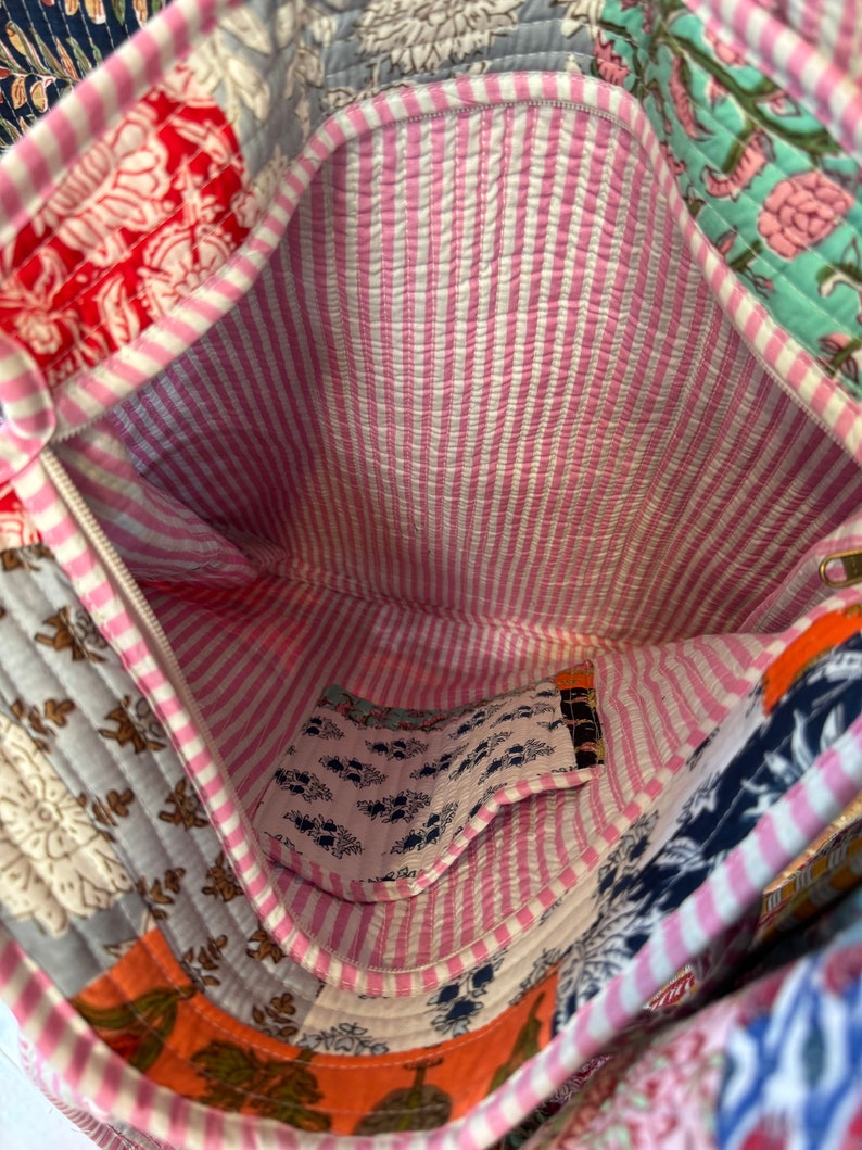 May include: A pink and white striped fabric bag with a patchwork design. The bag has a zipper closure and a small pocket inside. The bag is made of cotton and is perfect for carrying everyday essentials.