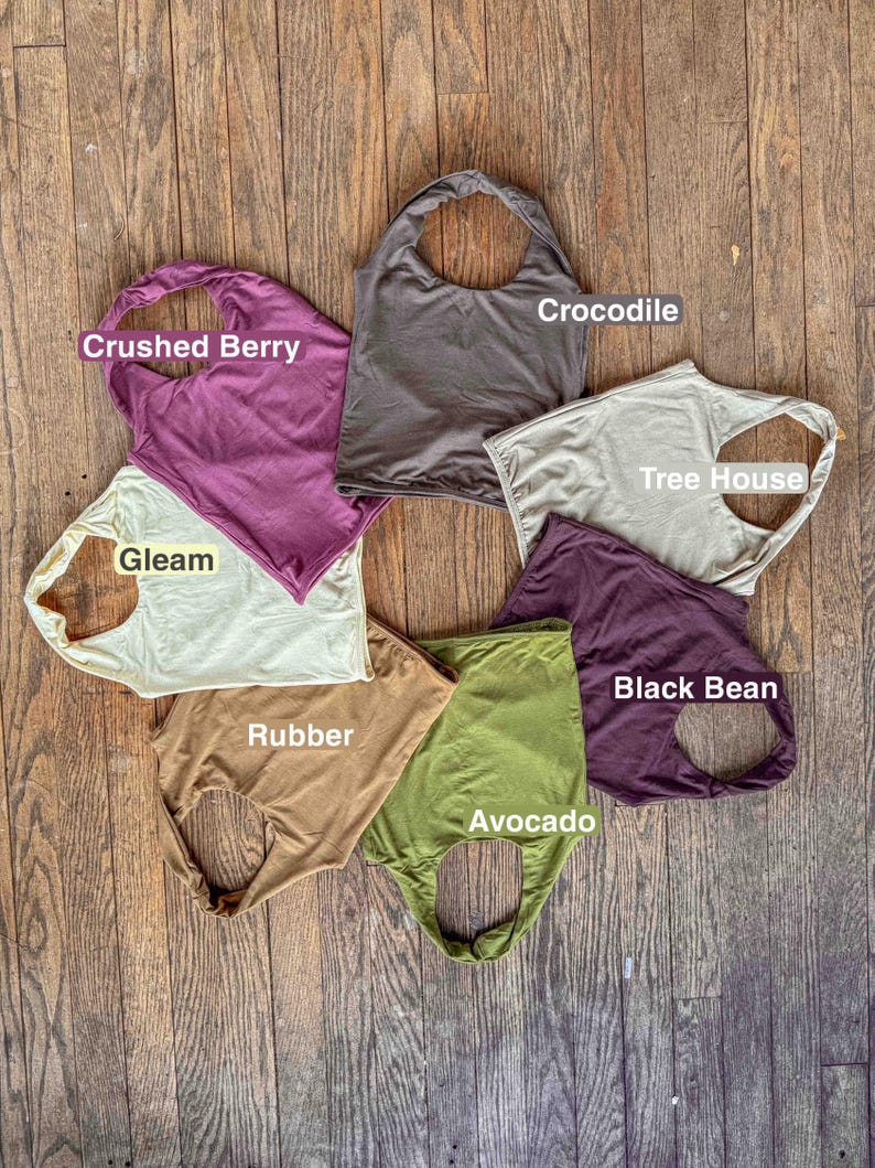 K&ouml;nnte beinhalten: Sieben &auml;rmellose Oberteile, die in einem Kreis angeordnet sind und jeweils mit einem Farbnamen beschriftet sind: Crushed Berry, Crocodile, Tree House, Black Bean, Avocado, Rubber und Gleam. Die Oberteile bestehen aus einfarbigem Stoff.