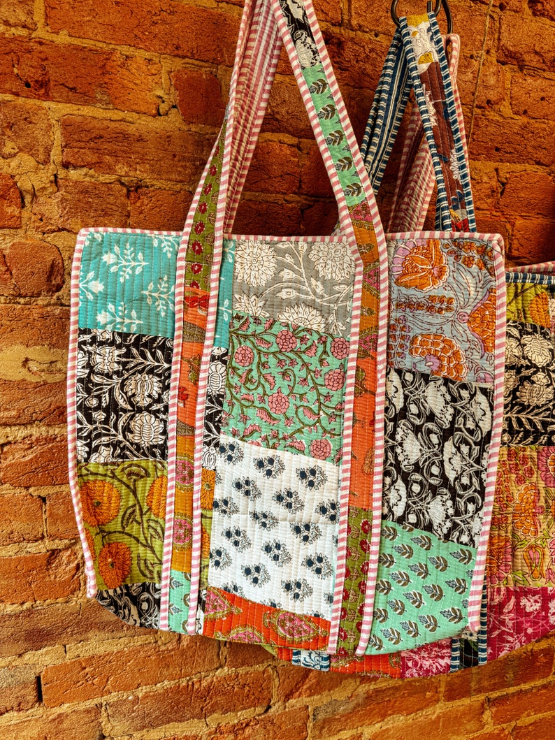 May include: A patchwork tote bag with a variety of colorful floral and geometric patterns. The bag has a long strap and is made of cotton fabric.