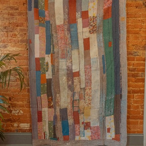 May include: A patchwork quilt with a variety of colors and patterns, including red, blue, green, and white. The quilt is made of different fabrics sewn together in a random pattern.