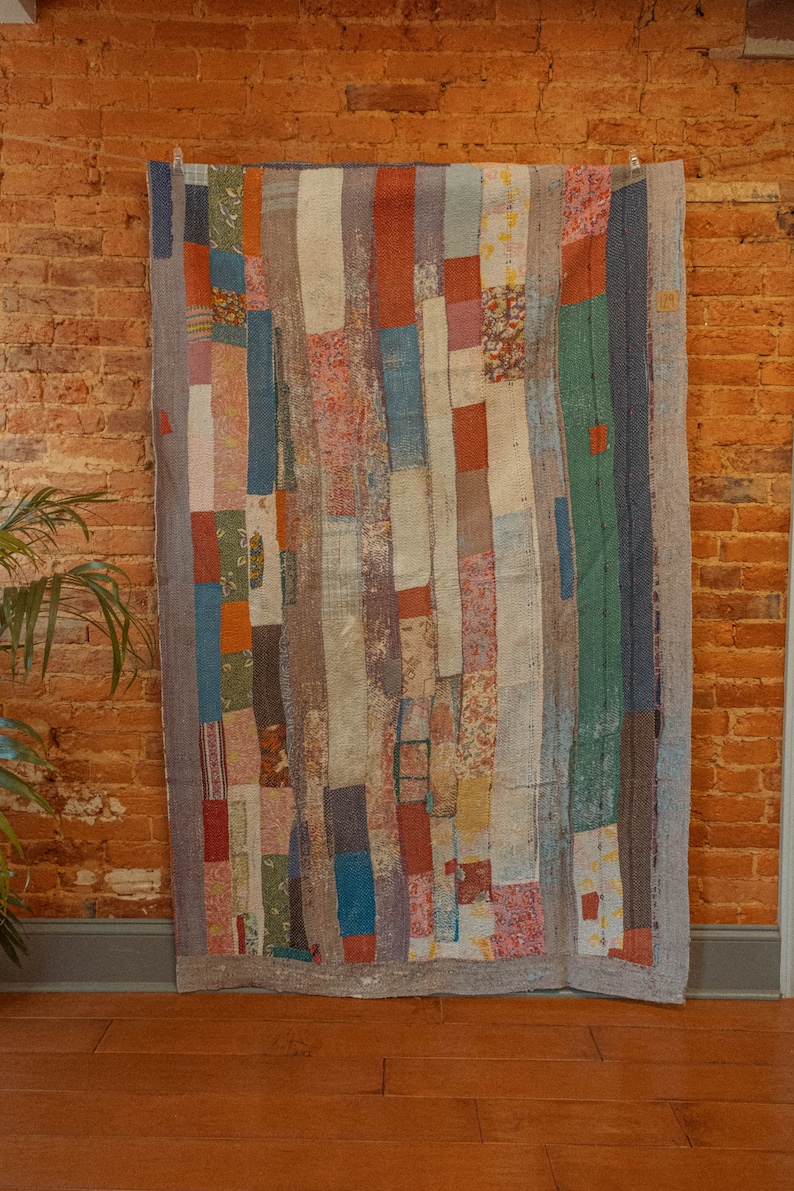 May include: A patchwork quilt with a variety of colors and patterns, including red, blue, green, and white. The quilt is made of different fabrics sewn together in a random pattern.