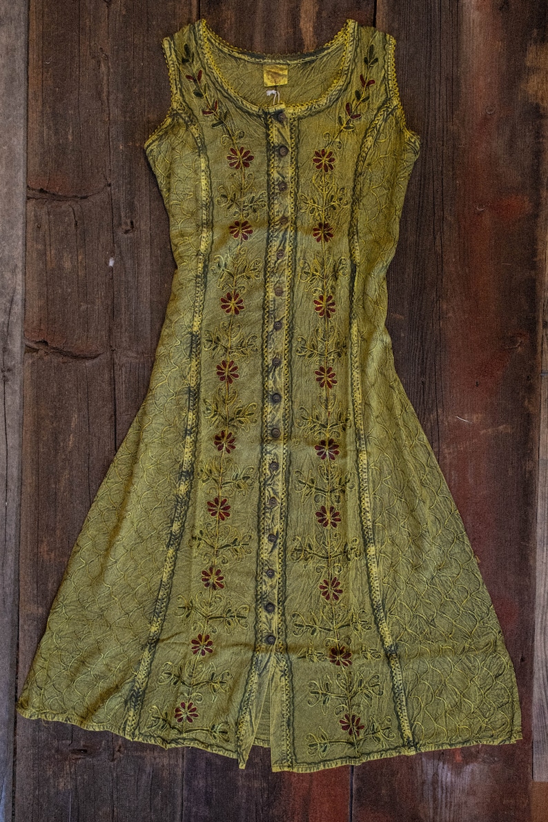May include: A sleeveless, green, button-up dress with floral embroidery. The dress has a loose fit and a flowing skirt.