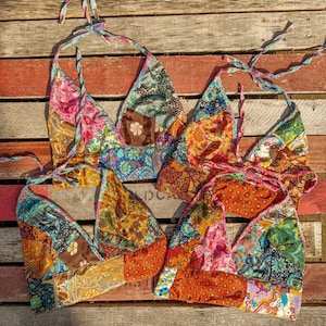 Pode incluir: Três tops halter de patchwork coloridos com fecho de nó. Os tops são feitos de diferentes tecidos e padrões, incluindo desenhos florais, paisley e geométricos. Os tops estão dispostos sobre uma superfície de madeira.