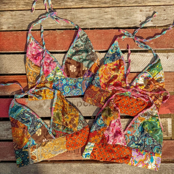 May include: Three colorful patchwork halter tops with a tie closure. The tops are made of different fabrics and patterns, including floral, paisley, and geometric designs. The tops are laid out on a wooden surface.