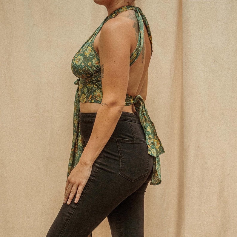 May include: A green and yellow floral print halter top with a tie back. The top is worn with black jeans.