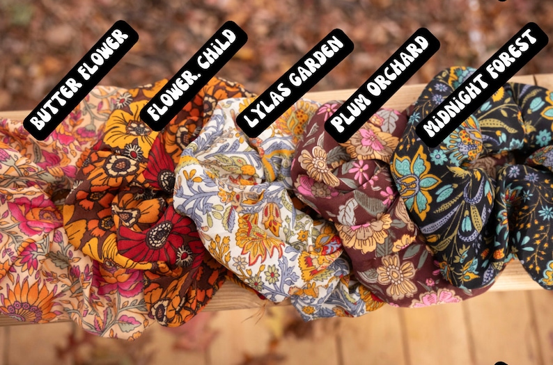 May include: Five colorful fabric scrunchies with floral patterns. The scrunchies are labeled "Butter Flower", "Flower Child", "Lylas Garden", "Plum Orchard", and "Midnight Forest".