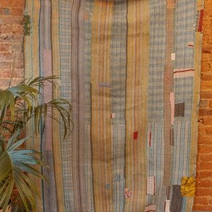 K&ouml;nnte beinhalten: Ein Vintage-Kantha-Steppdecke mit Patchwork-Design mit blauen, gelben und rosa Streifen. Die Steppdecke ist aus recycelten Saris gefertigt und hat einen rustikalen, handgen&auml;hten Look.