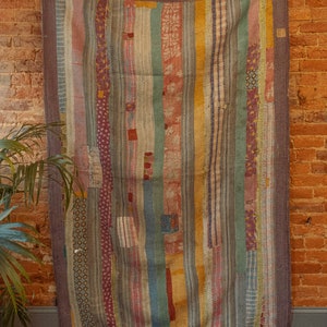 May include: A vintage patchwork quilt with a striped pattern in shades of blue, green, red, and yellow. The quilt is made of various fabrics and has a rustic, handmade look.