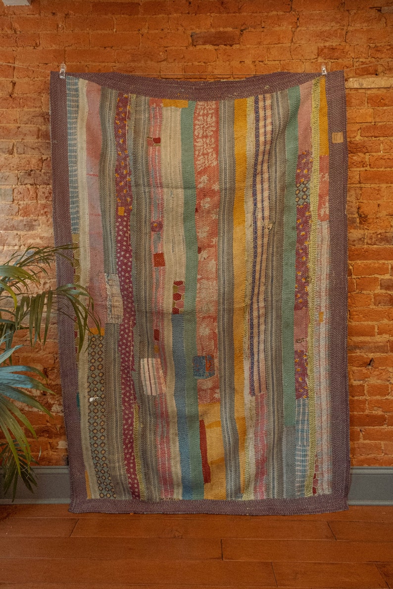May include: A vintage patchwork quilt with a striped pattern in shades of blue, green, red, and yellow. The quilt is made of various fabrics and has a rustic, handmade look.