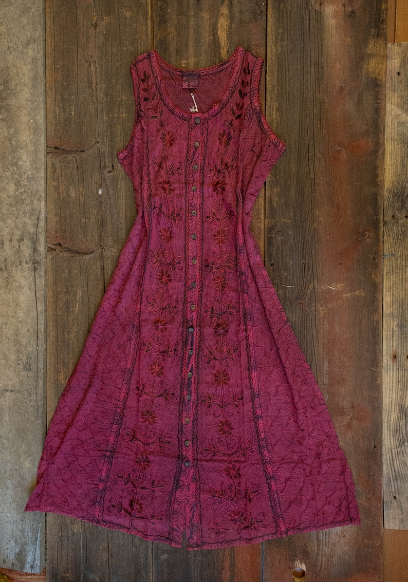 May include: A long, sleeveless, burgundy dress with a button-up front and floral embroidery. The dress has a flowing, A-line silhouette.