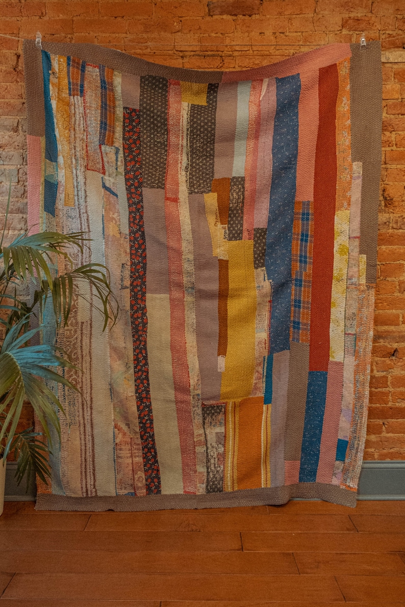 K&ouml;nnte beinhalten: Ein farbenfroher Patchwork-Deckenbezug mit vertikalen Streifen in Blaut&ouml;nen, Rot, Braun, Gelb und Rosa. Die Decke besteht aus verschiedenen Stoffen und Texturen, was ein einzigartiges und interessantes Design ergibt.