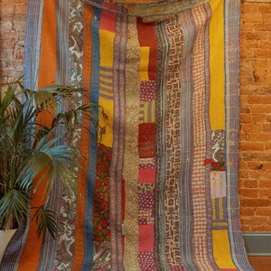 K&ouml;nnte beinhalten: Ein farbenfroher Patchwork-Deckenbezug mit vertikalen Streifen in Orange-, Gelb-, Blau- und Rott&ouml;nen. Der Bezug besteht aus verschiedenen Stoffen und Mustern und hat einen rustikalen, Vintage-Look.