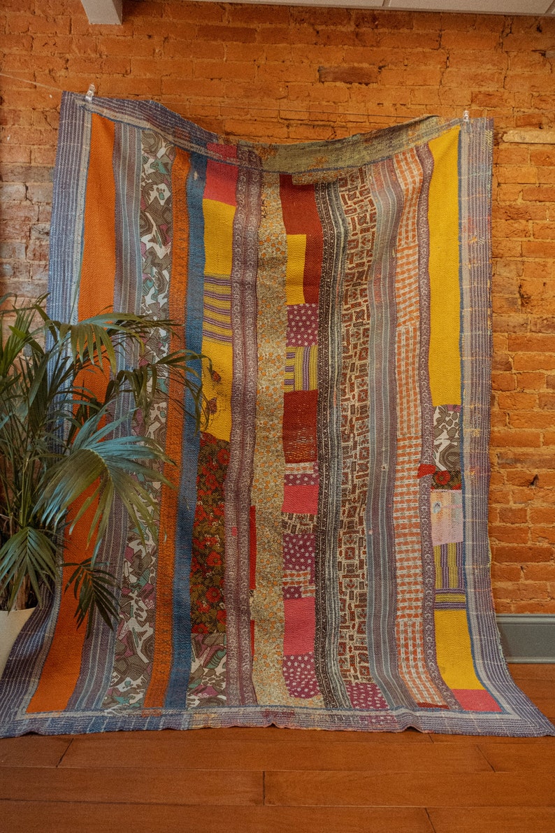 K&ouml;nnte beinhalten: Ein farbenfroher Patchwork-Deckenbezug mit vertikalen Streifen in Orange-, Gelb-, Blau- und Rott&ouml;nen. Der Bezug besteht aus verschiedenen Stoffen und Mustern und hat einen rustikalen, Vintage-Look.