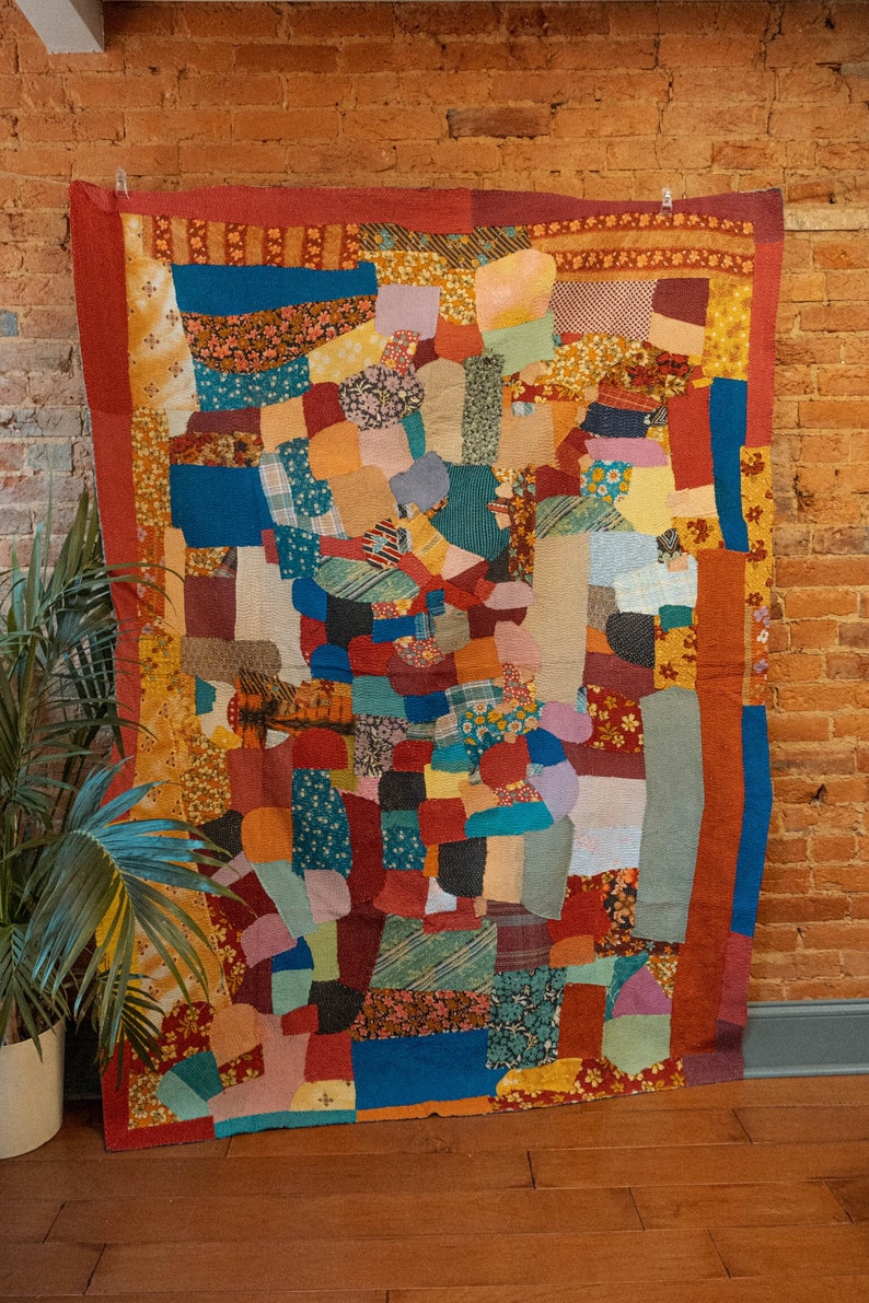 K&ouml;nnte beinhalten: Ein farbenfroher Patchwork-Deckenbezug mit einer Vielzahl von Stoffen und Mustern, darunter florale, geometrische und karierte Designs. Die Decke besteht aus vielen verschiedenen Farben, darunter Rot, Orange, Gelb, Gr&uuml;n, Blau und Lila.