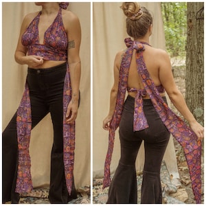May include: A purple and orange floral print halter top with long ties that can be worn as a wrap skirt. The top is shown being worn with black bell bottom pants.