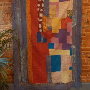 May include: A colorful patchwork quilt with a variety of fabrics in shades of blue, red, yellow, purple, and white. The quilt is made up of squares and rectangles of different sizes and is sewn together with a simple stitch.