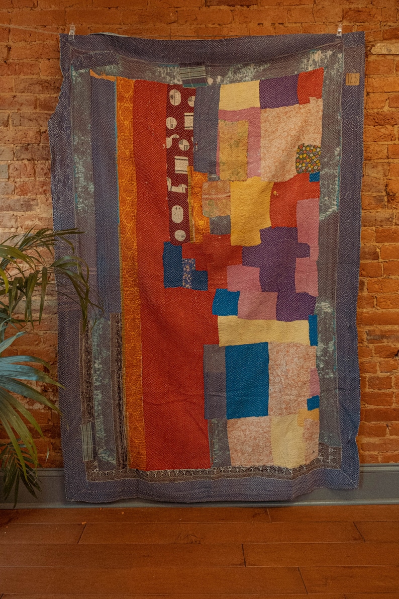 May include: A colorful patchwork quilt with a variety of fabrics in shades of blue, red, yellow, purple, and white. The quilt is made up of squares and rectangles of different sizes and is sewn together with a simple stitch.