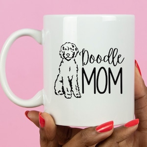 Op de afbeelding: Witte keramische koffiemok met een zwart silhouet van een poedel en de tekst "Doodle MOM" in zwart.