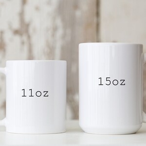 May include: Two white ceramic mugs with black text. The smaller mug says "11oz" and the larger mug says "15oz".