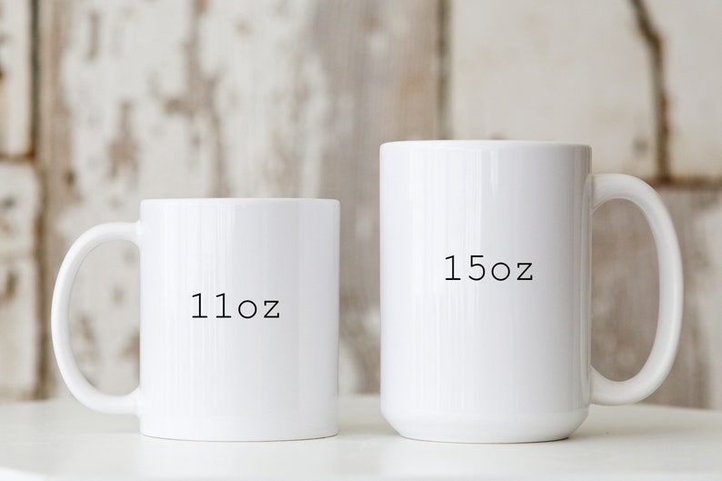 May include: Two white ceramic mugs with black text. The smaller mug says "11oz" and the larger mug says "15oz".