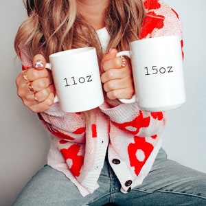 May include: Two white ceramic mugs with black text. The mug on the left says "11oz" and the mug on the right says "15oz".