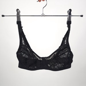 May include: Black lace bra hanging on a silver hanger with black clips.