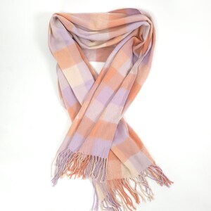 May include: A soft, pastel-colored scarf with a plaid pattern. The scarf features a combination of peach, lavender, and cream squares. The ends of the scarf have a fringe detail. This accessory is suitable for cooler weather.