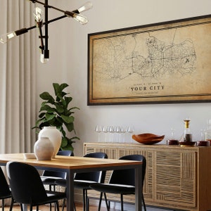 May include: A vintage-style map print of a city with a black frame. The map is printed on a beige background with black lines representing roads and streets. The text "YOUR CITY" is printed in black at the bottom of the map, along with the coordinates "32.6191&deg; N, 117.1988&deg; W" and "STATE OR COUNTRY".