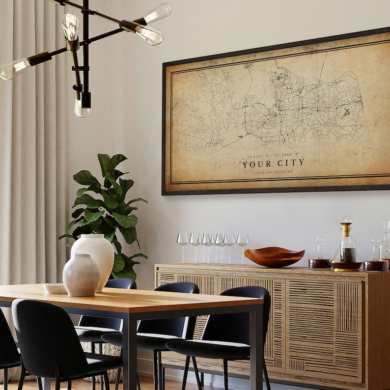 May include: A vintage-style map print of a city with a black frame. The map is printed on a beige background with black lines representing roads and streets. The text "YOUR CITY" is printed in black at the bottom of the map, along with the coordinates "32.6191&deg; N, 117.1988&deg; W" and "STATE OR COUNTRY".