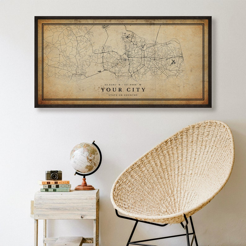 May include: A vintage-style map print in a brown frame, featuring a detailed map of a city with roads and streets. The map is printed on a beige background with a brown border. The text "YOUR CITY" is printed below the map, along with coordinates and the state or country.