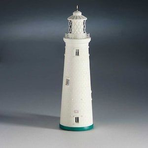 Op de afbeelding: Wit model van een vuurtoren met een groene basis en zwarte raamdetails. De vuurtoren is gemaakt van een getextureerd materiaal dat op steen lijkt.