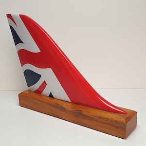 Op de afbeelding: Een model vliegtuigstaartvin, met een rood, wit en marineblauw ontwerp, gemonteerd op een rechthoekige houten basis. Het ontwerp toont de Union Jack, een symbool van het Verenigd Koninkrijk.