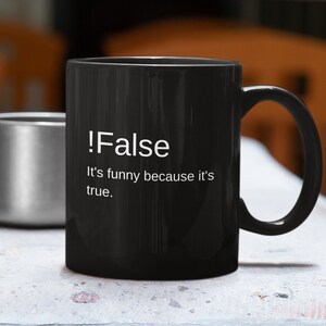 May include: A black coffee mug with a white design that says "!False It's funny because it's true."