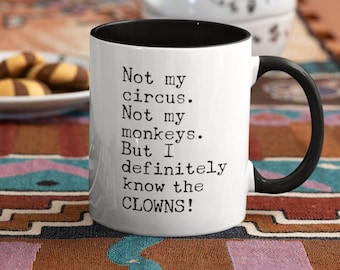 May include: White ceramic mug with a black rim and handle. The mug has black text that reads "Not my circus. Not my monkeys. But I definitely know the CLOWNS!"