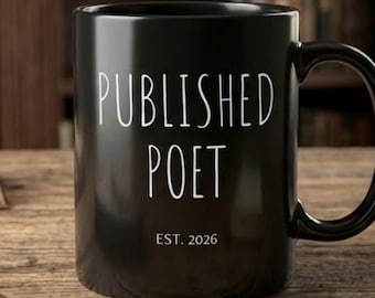 May include: A black ceramic mug featuring the white text "PUBLISHED POET" in a tall, sans-serif font, with the smaller white text "EST. 2026" positioned directly below the main lettering. The mug has a smooth finish and a curved handle on the right.