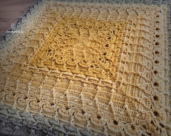 May include: A handmade crochet blanket with a gradient of colors, transitioning from a light cream to a golden yellow center, and a gray border. The blanket features intricate stitch patterns and a textured surface.