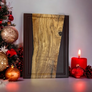 May include: A rectangular wooden cutting board with a dark brown epoxy resin inlay. The board has a natural wood grain pattern and is framed with a dark brown border.