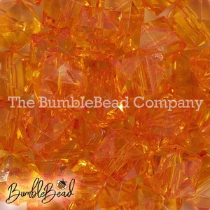 May include: A close-up image of a pile of orange, faceted, glass beads. The beads are clear and have a slight shimmer to them. The beads are all the same size and shape.