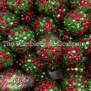 May include: Close-up of a group of green and red Christmas-themed beads covered in rhinestones. The beads are arranged in a random pattern and are all the same size.