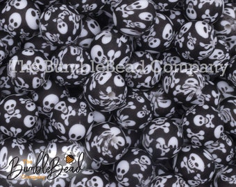 May include: A collection of black and white skull-patterned beads. The beads are round and feature a repeating design of skulls and crossbones. The BumbleBead Company logo is visible at the bottom of the image. These beads are suitable for jewelry making and crafting.