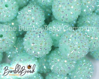 May include: Close-up of mint green, textured beads with sparkling iridescent accents. The beads are round with a hole for stringing. The BumbleBead Company logo is visible in the image.