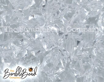 May include: A close-up image of a pile of clear, faceted, crystal beads. The beads are all the same size and shape, and they are arranged in a random pattern.