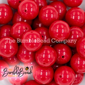 May include: A close-up of a pile of large, bright red, round, plastic beads. The beads are smooth and shiny, and they have a small hole in the center. The beads are perfect for making jewelry, crafts, and other projects.