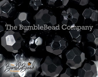 May include: A close-up of a pile of black faceted glass beads. The beads are all the same size and shape, and they have a shiny, polished finish.