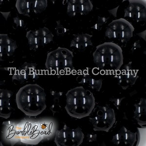 May include: A close-up image of a large quantity of black round beads. The beads are smooth and shiny, and they are all the same size. The beads are arranged in a random pattern, and they are all in focus.